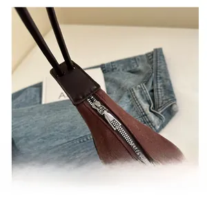 Detail of silver smooth zipper and brown suede material on the crescent shoulder bag