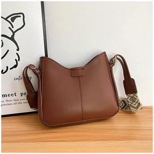Brown faux leather crossbody bag with geometric tribal pattern wide strap in a minimalist setting