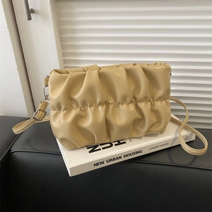 Cream pleated cloud bag with wave texture and silver hardware on a minimalist background