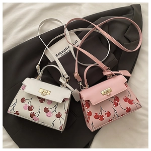 Détail de sacs à bandoulière imprimé cerise rose et blanc avec fermoirs rotatifs dorés