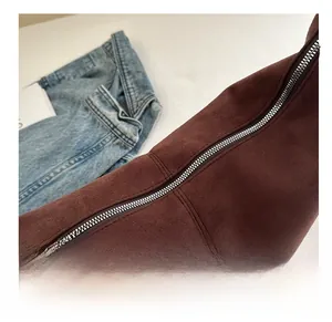 Close-up of premium dark brown suede fabric texture and durable metal zipper detail