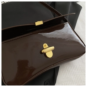 Detail of vintage gold swivel lock and high-gloss brown patent leather on shoulder bag