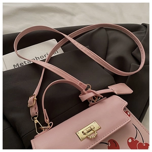Détail du sac à bandoulière en cuir PU rose avec motif cerise et boucle dorée en métal