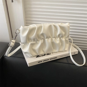 White pleated cloud shoulder bag with silver hardware on minimalist urban background