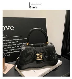 Detail of black wave patterned handbag with golden double M logo and leather strap