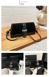 Close-up of black suede underarm bag featuring a silver H-shaped metal buckle detail