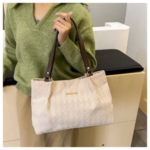 Dettaglio della borsa tote trapuntata bianco sporco con manici in pelle marrone e dettagli oro