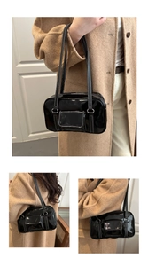 Detail of black glossy shoulder bag featuring white contrast stitching and pocket
