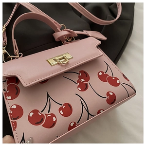 Détail du sac à main rose à motif cerises avec boucle dorée et texture cuir PU