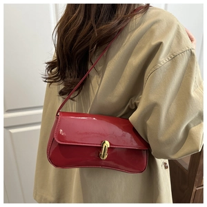 Detail view of red patent leather shoulder bag with golden metallic lock and glossy finish