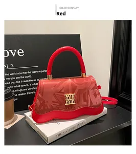 Detail of red leather handbag with wave edge and embossed logo in a lifestyle setting
