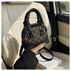 Detailed view of mini shell bag with brown monogram pattern and black leather trim