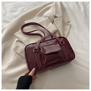 Close-up of wine red retro handbag with white contrast stitching and silver hardware