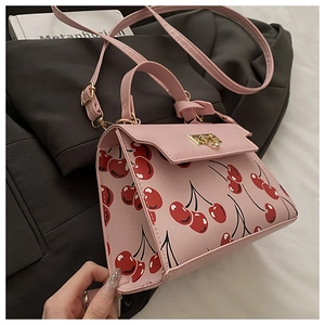 Détail du sac rose à motif cerises avec fermoir en métal et bandoulière réglable