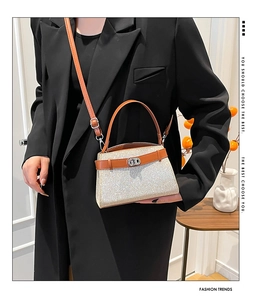 Detail of sequin woven handbag with brown leather strap and silver twist lock