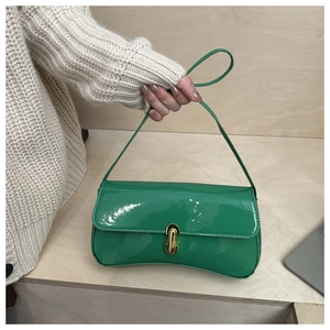 Detail of emerald green patent leather handbag with gold metal lock and sleek finish