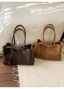 Detail of large suede tote bags in coffee and camel on a soft white rug scene