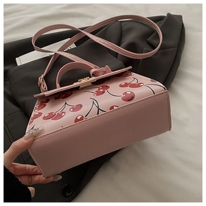 Détail du sac à main rose à motif cerises avec fermoir doré et bandoulière