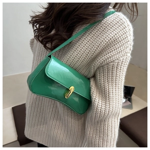 Detail of emerald green patent leather shoulder bag with a gold rectangular metal clasp