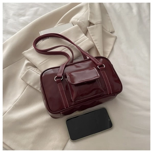 Detail of burgundy glossy shoulder bag with white contrast stitching and mini front pocket