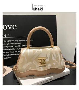 Close-up of khaki handbag featuring wave-shaped bottom and gold metal logo detail
