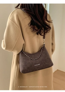 Dettaglio della borsa tote marrone scuro con catena indossata da una modella in foto