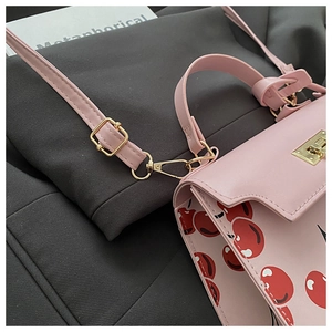 Gros plan du sac rose à motif cerise avec fermoir doré et finitions de couture