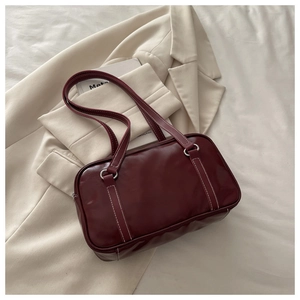 Detail of dark red handbag with white contrast stitching and silver metal ring hardware