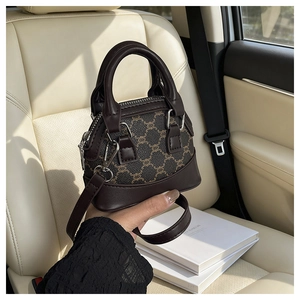 Dettaglio di una mini borsa a conchiglia marrone stampata con dettagli in metallo e manici