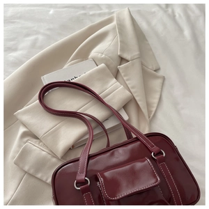 Close-up of a burgundy patent leather tote with white contrast stitching and front pocket