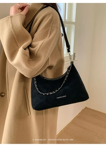 Dettaglio borsa tote nera opaca con catena d'argento indossata da modella in cappotto