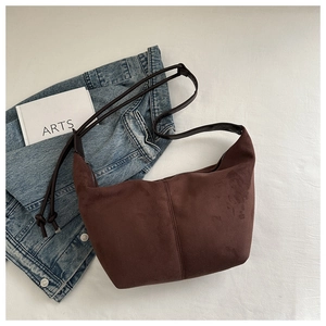 Detail view of deep brown suede tote bag with leather straps on a minimalist setting
