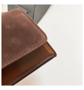 Close-up of vintage brown bag showing suede flap and smooth leather texture contrast