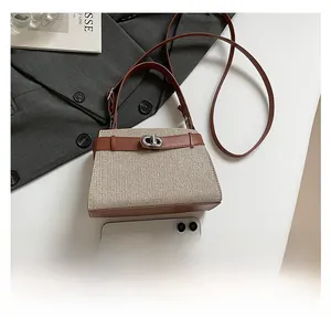 Detail view of woven mini Kelly tote bag with leather trim next to a smartphone for size