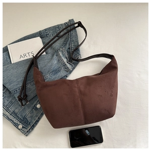 Detail of a dark brown suede hobo bag featuring vertical stitching and a knotted strap