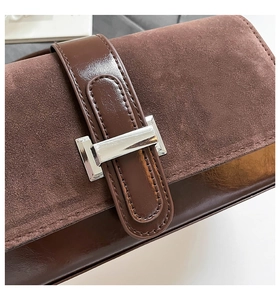 Macro view of dark brown vintage baguette bag with suede flap and silver metal buckle