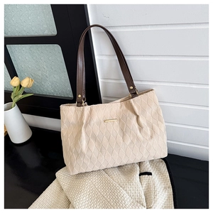 Dettaglio borsa tote trapuntata beige con manici marroni e decorazione in metallo oro