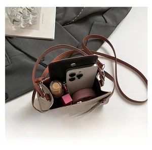 Detail showing internal capacity of the khaki woven crossbody bag with daily essentials