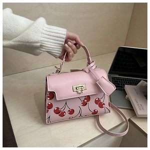 Sac à main rose imprimé cerises avec fermoir doré en situation d'utilisation