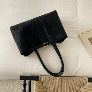 Vintage matte black tote bag with long straps and metal buckle on white fabric background
