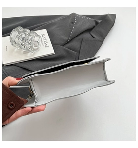 Detail view of the slim side profile and stitching of this minimalist grey crossbody bag