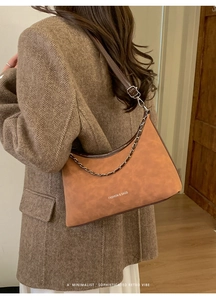 Dettaglio borsa a mezzaluna marrone chiaro vintage con catena su cappotto di lana spigata