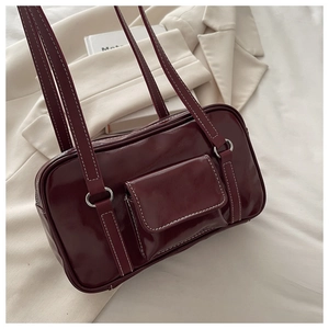 Detail of dark red glossy shoulder bag featuring distinctive white contrast stitching