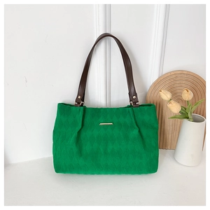 Dettaglio borsa tote trapuntata verde con manici in pelle marrone e fibbie dorate