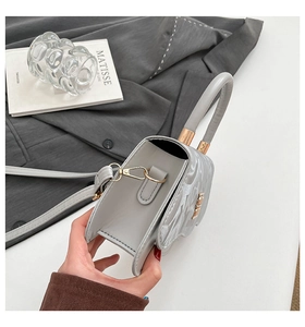 Detailed side view of grey semi-circular bag with tubular handle and golden metal hook