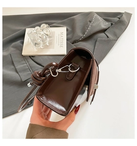 Detailed side view of vintage dark brown baguette bag with silver twist lock and knotted handle