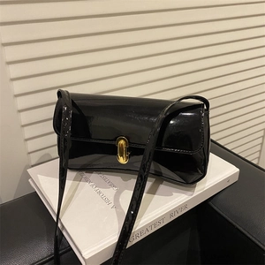 Elegant black patent leather shoulder bag with gold metal buckle on a minimalist setting
