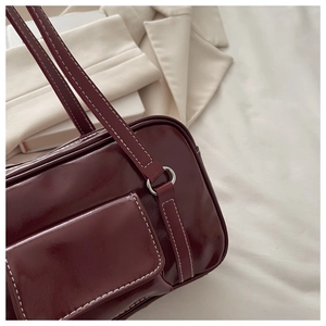 Detail of dark red faux leather shoulder bag with white contrast stitching and silver ring