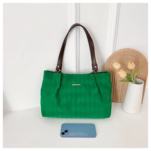 Dettagli di una borsa tote verde trapuntata con manici marroni e finiture dorate