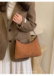 Borsa hobo marrone con tracolla a catena e logo, indossata da modella in stile vintage